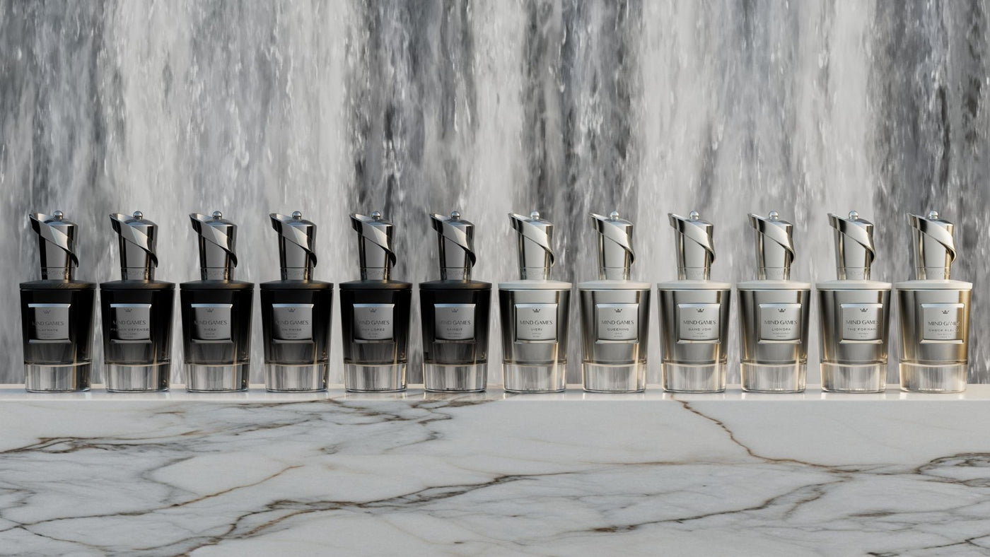 Row of silver Mind Games perfume bottles on a marble surface with a marble wall background