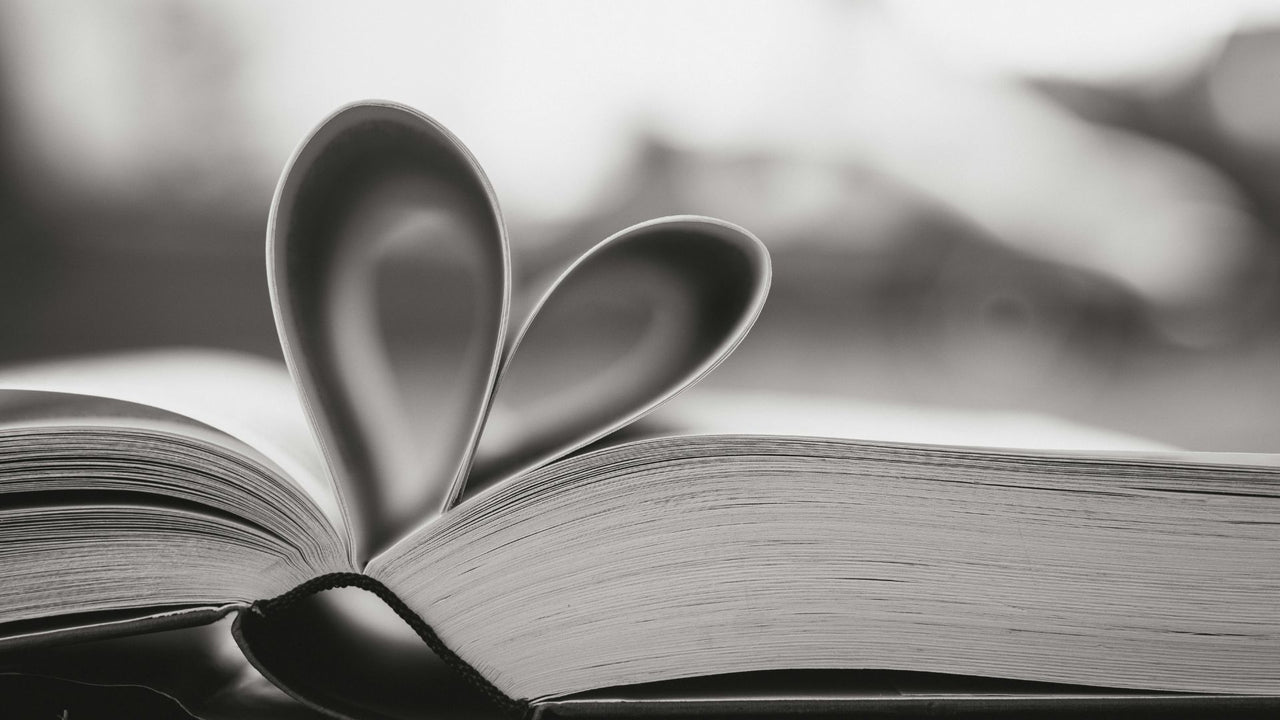 Open book with pages folded into a heart shape on a blurred background